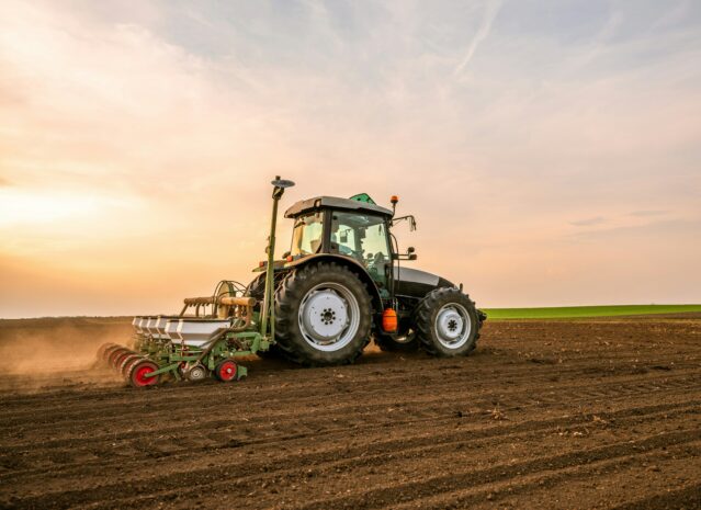 Tractor ploughing field during sunrise